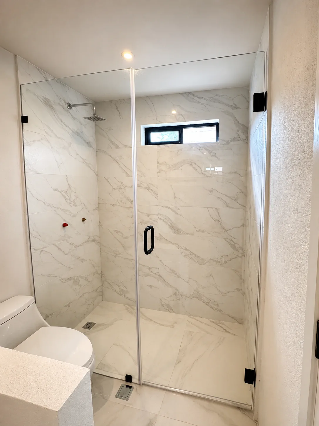 Cancel de baño de cristal templado con herrajes negros en baño moderno